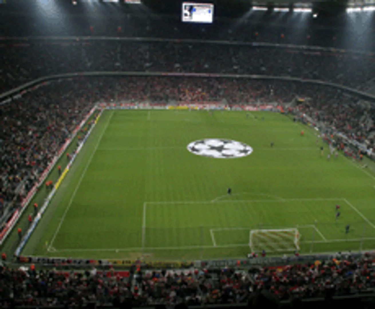 Un estadio de fútbol con una gran pantalla y un logotipo en el centro del campo de juego.