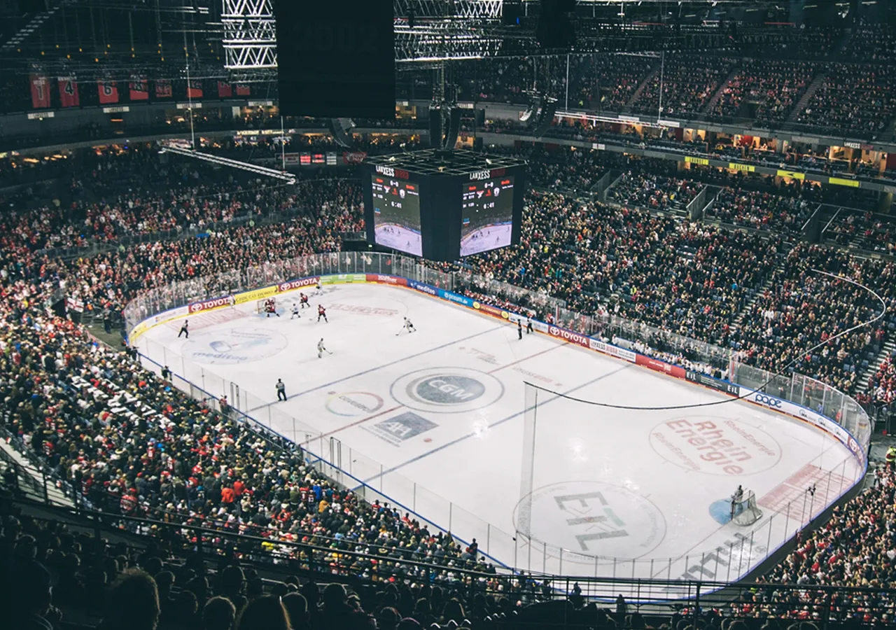 Una vista amplia de una pista de hielo durante un partido de hockey con una gran multitud.