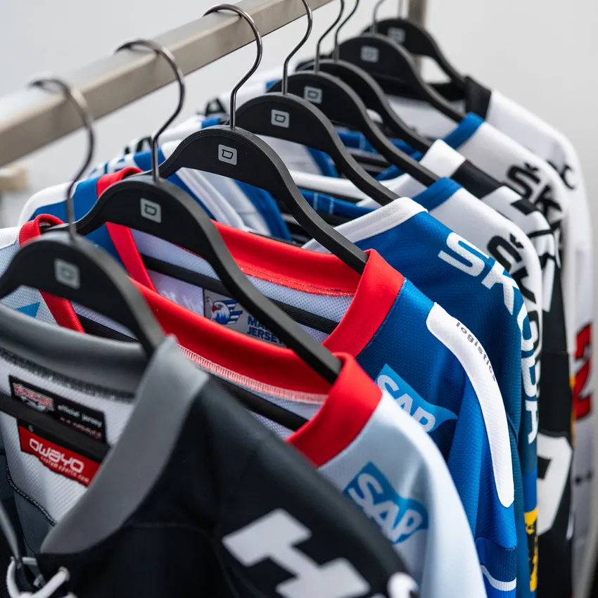 Una fila de varias camisetas deportivas de colores colgadas en una percha.