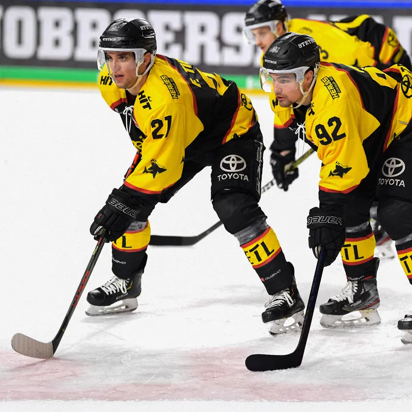 Dos jugadores de hockey sobre hielo con camisetas amarillas y negras están en el hielo.