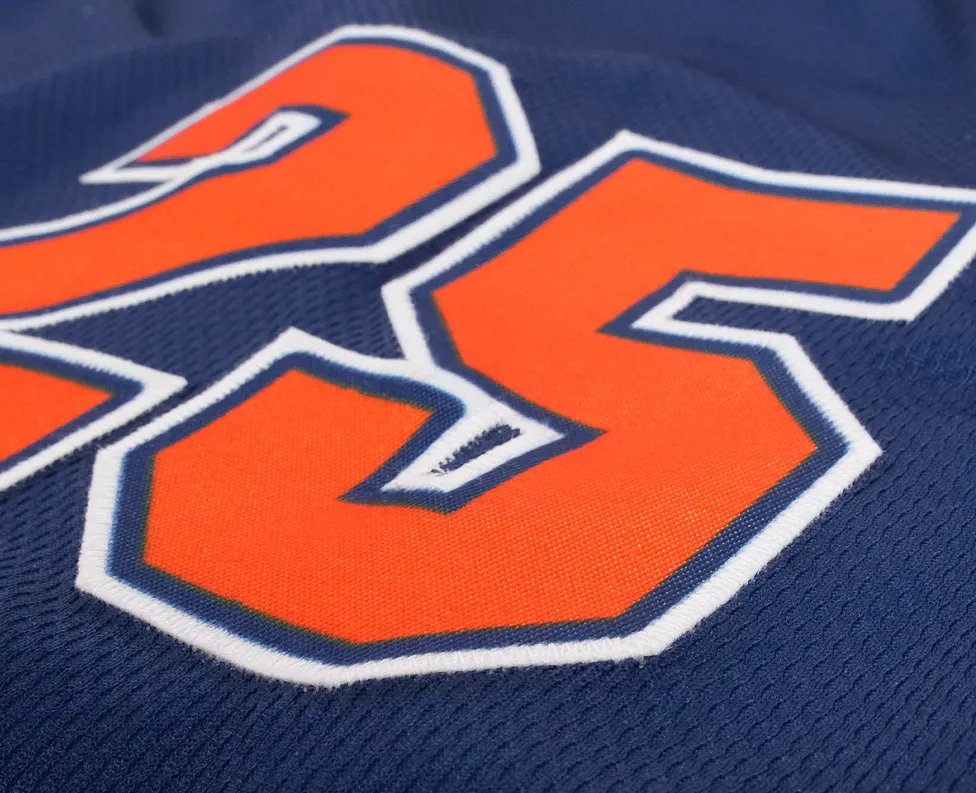 Acercamiento de una camiseta deportiva azul con el número 25 en naranja brillante.