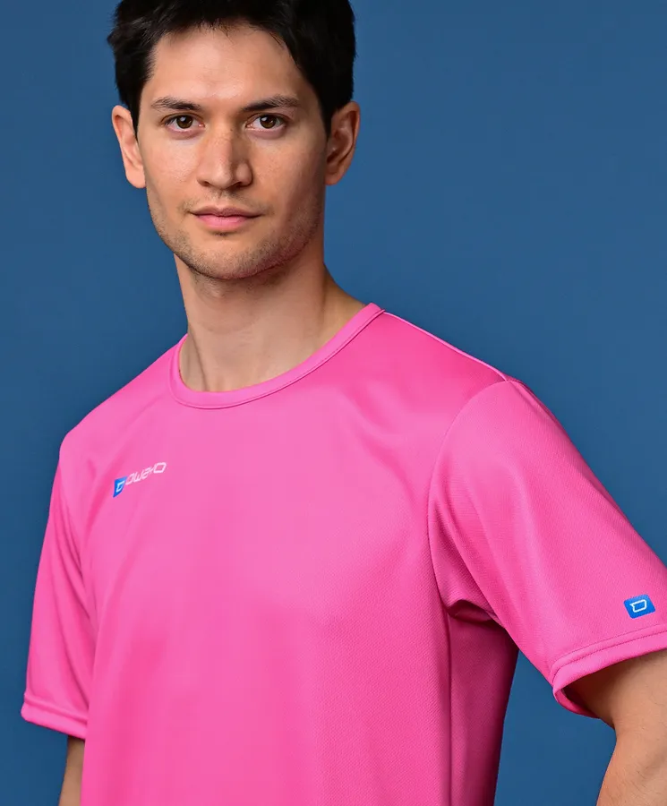 Un hombre lleva una camiseta deportiva rosa brillante frente a un fondo azul.
