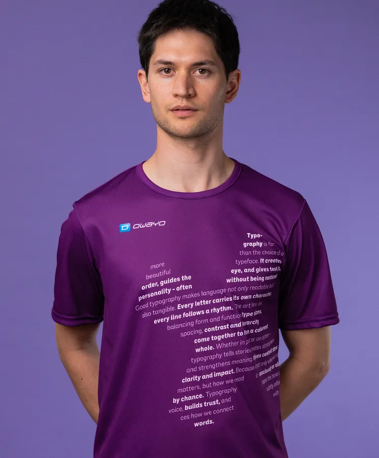 Un hombre lleva una camiseta deportiva morada con texto tipográfico en la parte delantera, frente a un fondo morado.