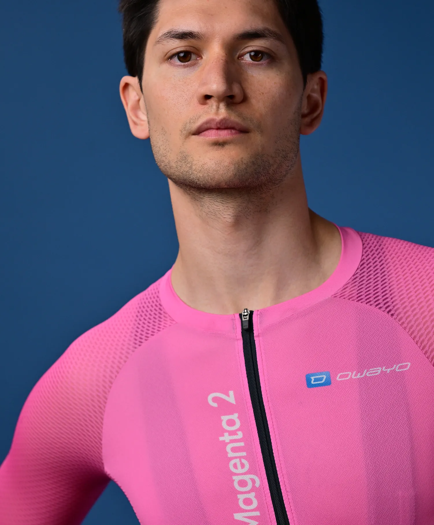 Un hombre lleva una camiseta deportiva rosa sin mangas con cremallera y el logotipo 'owayo' en el pecho.