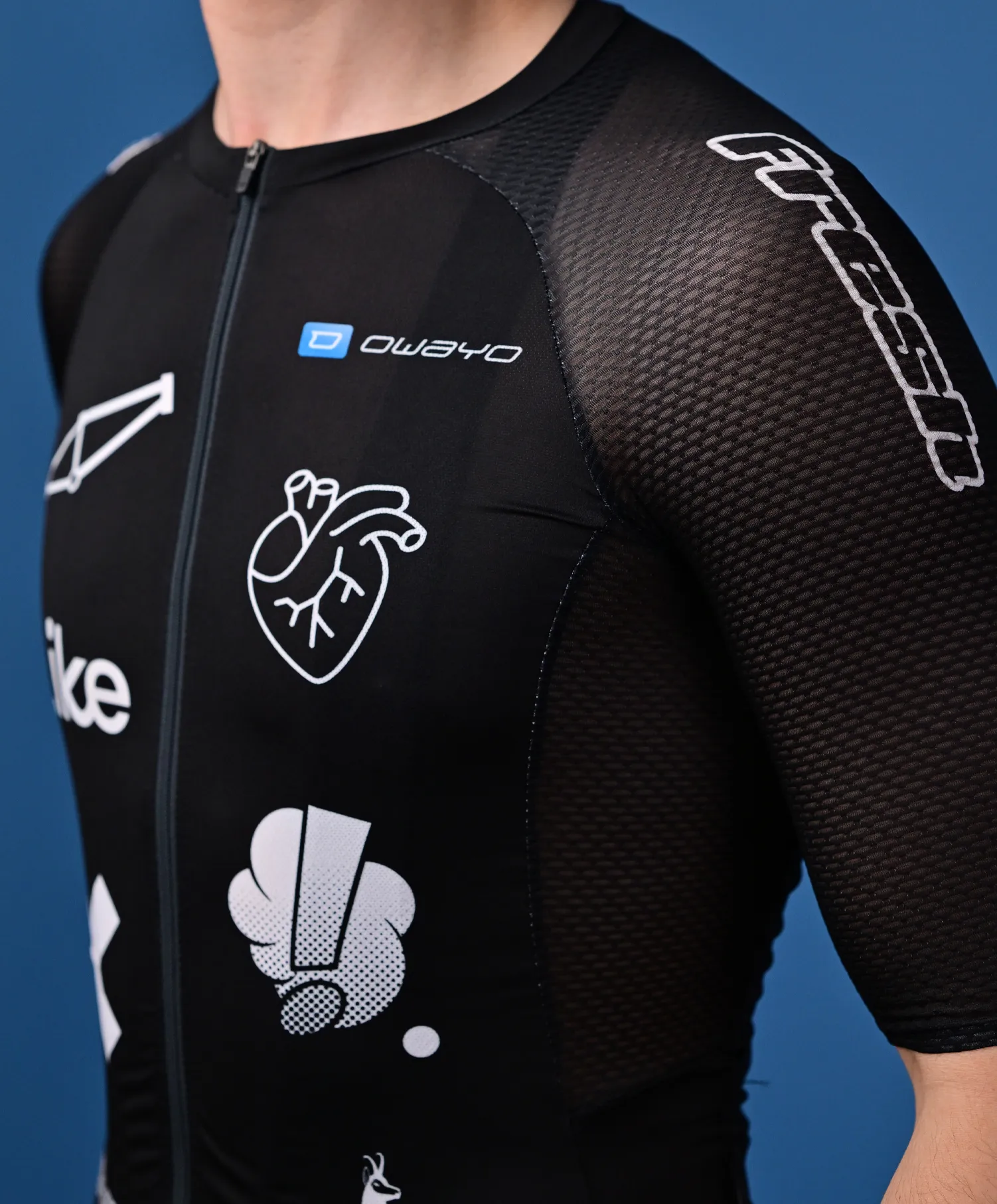 Una persona lleva una camiseta deportiva negra sin mangas de owayo con cremallera frontal, que presenta varios logotipos y gráficos blancos, incluyendo un corazón y una 'O' estilizada, en el pecho y el brazo.
